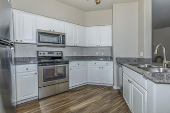 An empty kitchen with white cabinets and stainless steel appliances