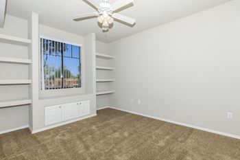 An empty living room with carpet and a ceiling fan