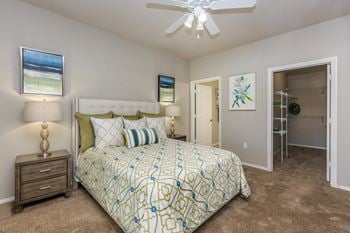 A bedroom with a bed and a ceiling fan