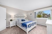 Middletown apartment for rent - A bedroom with a white bed and a window with a view of a house.