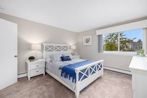 Middletown apartment for rent - A bedroom with a white bed and a window with a view of a house.