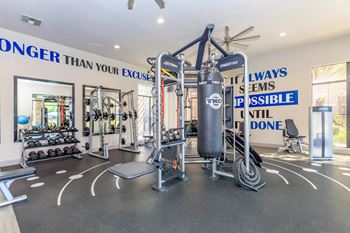A home gym with weights and cardio equipment and a wall with a quote on it