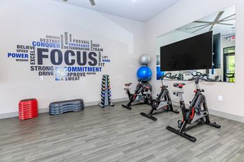 A fitness room with exercise bikes and a tv