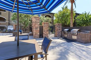 A patio with a table and chairs and a blue and white umbrella