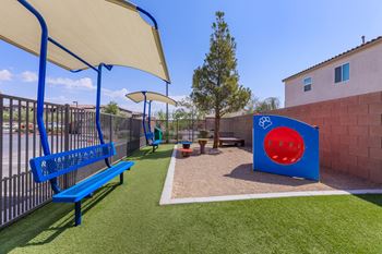 A playground with a blue bench and a playset and umbrella