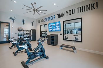 Yoga and spin studio with a row of stationary bikes and a tv screen on the wall