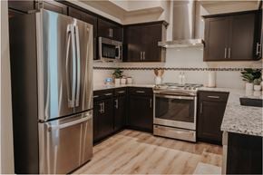 Las Vegas apartment for rent - Modern kitchen with stainless gas range, overhead hood, microwave, and refrigerator at Level 25 at The Curve by Picerne, Las Vegas