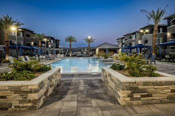 Night shot of the beautiful resort-style pool surrounded by palm trees and cabanas