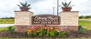 Liberty Hill apartment for rent - A sign for Liberty Trails Townhomes with a brick pillar and a plant on top.