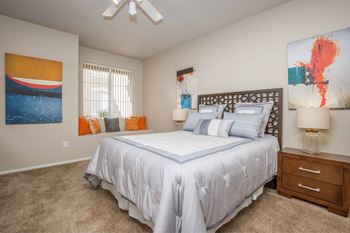 A bedroom with a white bed and a ceiling fan