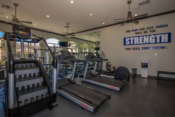 A gym with cardio equipment and a wall with the quote the pain will heal today