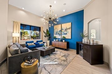Las Vegas apartment for rent - A living room with a grey sofa, a blue couch, a coffee table, a chandelier, and a painting on the wall.