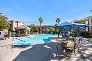 Las Vegas apartment for rent - A swimming pool with a blue umbrella and chairs around it.
