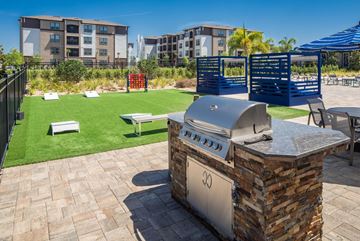 Zephyrhills apartment for rent - A BBQ grill is in the middle of a patio with a building in the background.