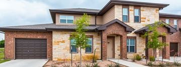 Liberty Hill apartment for rent - A modern house with a brick facade and a large garage door.