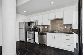Dallas apartment for rent - a kitchen with white cabinets and stainless steel appliances