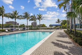 Miami apartment for rent - A sparkling swimming pool surrounded by palm trees and brick walkways at Blue Lagoon 7 Apartments in Miami, FL