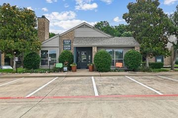 Plano apartment for rent - A building with a sign that says "Leasing Center" is surrounded by trees and has a parking lot in front.