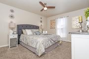 Bossier City apartment for rent - A carpeted bedroom with a large bed and ceiling fan at The Drake in Bossier City, LA