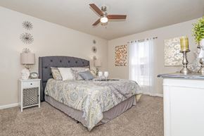 Bossier City apartment for rent - A carpeted bedroom with a large bed and ceiling fan at The Drake in Bossier City, LA