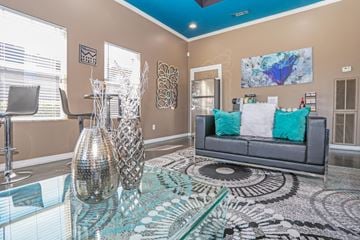 Bossier City apartment for rent - A clubhouse with a grey couch and a large painting on the wall at The Drake in Bossier City, LA
