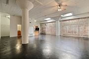 Dallas apartment for rent - A large empty room with a ceiling fan and a brick wall.