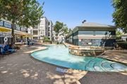 Richardson apartment for rent - A sparkling swimming pool with apartment buildings in the background at Encore at Buckingham Apartments in Richardson, TX