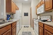 Richardson apartment for rent - Windsor kitchen with wooden cabinets and white appliances at Encore at Buckingham Apartments in Richardson, TX