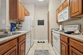 Richardson apartment for rent - Windsor kitchen with wooden cabinets and white appliances at Encore at Buckingham Apartments in Richardson, TX