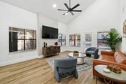 Irving apartment for rent - A living room with a grey armchair, a brown leather couch, a wooden coffee table, and a flat screen TV mounted on the wall.