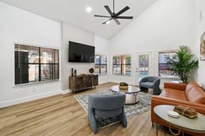 Irving apartment for rent - A living room with a grey armchair, a brown leather couch, a wooden coffee table, and a flat screen TV mounted on the wall.