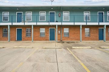 Waco apartment for rent - A parking lot in front of a building with blue doors.