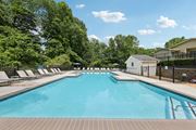 Duluth apartment for rent - A large swimming pool surrounded by trees and lounge chairs at Gwinnett Square Apartments in Duluth, GA