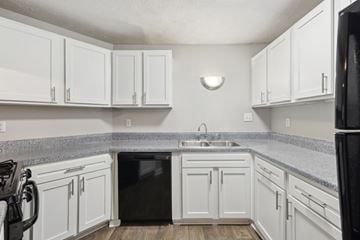 Duluth apartment for rent - A kitchen with white cabinets and a black fridge.