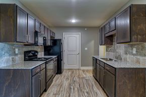 Canton apartment for rent - a kitchen with dark cabinets and granite counter tops and a door