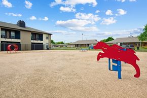 Waco apartment for rent - A red dog-shaped park equipment sits in the middle of a dog park at Heritage Square Apartments in Waco, TX