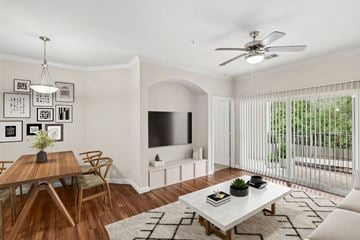 Conroe apartment for rent - A living room with a wooden dining table and chairs, a white sofa, a television, and a ceiling fan.