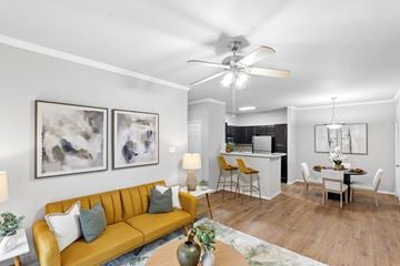 Houston apartment for rent - A living room with a yellow sofa and a dining table with chairs.