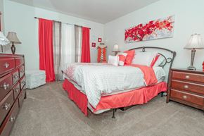 Shreveport apartment for rent - A bedroom with a large bed and red curtains at Laurel Parc apartments in Shreveport, LA.