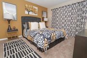 Shreveport apartment for rent - A bedroom with a patterned bedspread and a black and white rug at Magnolia apartments in Shreveport, LA