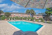Shreveport apartment for rent - A beautiful sunny day by a pool with a table and chairs under a canopy at Magnolia Apartments in Shreveport, LA
