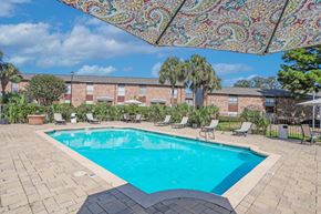 Shreveport apartment for rent - A beautiful sunny day by a pool with a table and chairs under a canopy at Magnolia Apartments in Shreveport, LA