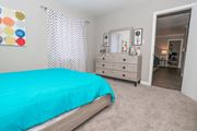 Shreveport apartment for rent - A cypress bedroom with a teal bedspread and a white dresser with mirror at The Marq in Shreveport, LA