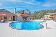 Shreveport apartment for rent - A large outdoor swimming pool surrounded by a patio area with lounge chairs and umbrellas at The Marq apartments in Shreveport, LA