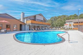 Shreveport apartment for rent - A large outdoor swimming pool surrounded by a patio area with lounge chairs and umbrellas at The Marq apartments in Shreveport, LA
