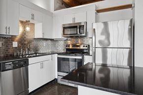 Dallas apartment for rent - Murray Lofts apartment kitchen with white cabinets, stainless steel appliances and black counter tops | Deep Ellum Lofts in Dallas, TX