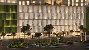 North Miami Beach apartment for rent - A modern building with a white facade and palm trees in front.