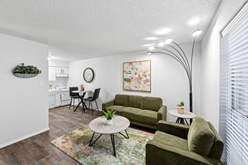 Denton apartment for rent - A living room with a green couch, a coffee table, and a painting on the wall.