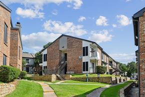 Denton apartment for rent - An apartment building with green lawns in front at The Oaks of Denton Apartments in Denton, TX