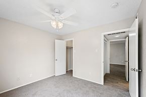 Dallas apartment for rent - a bedroom with a ceiling fan and a hallway in the background